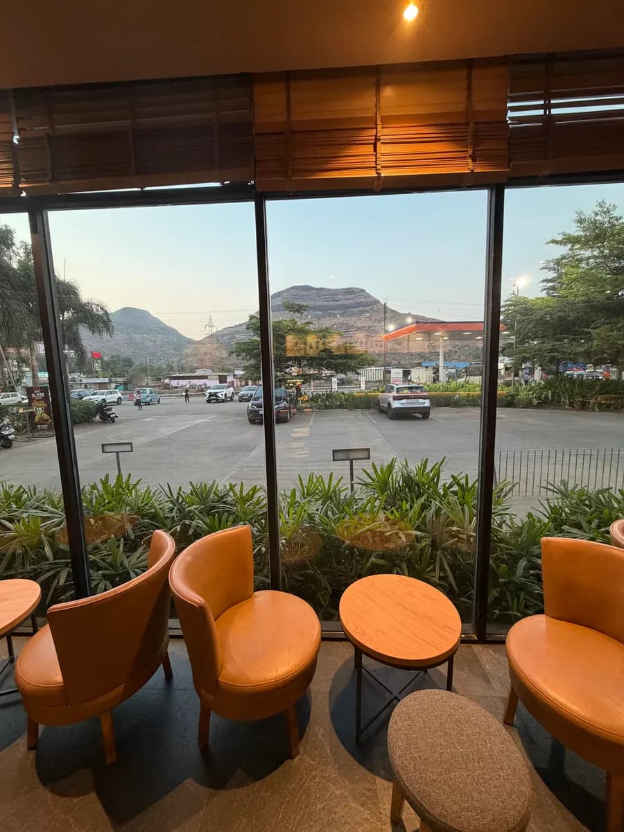 View from a roadside café window across a car park to the hills